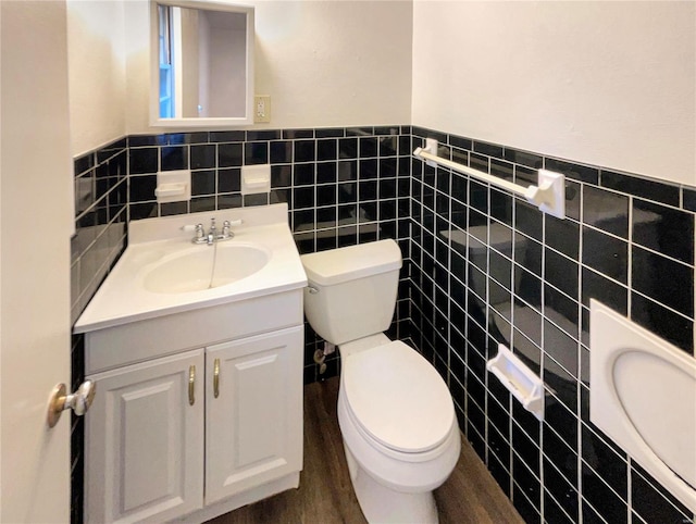 bathroom featuring tile walls, hardwood / wood-style floors, vanity, and toilet