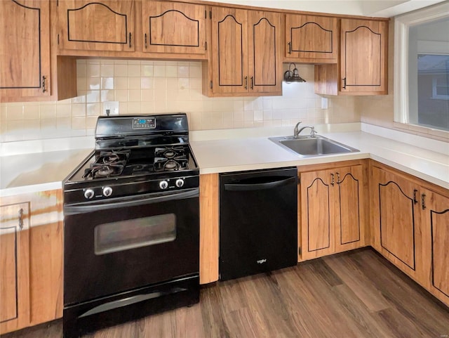 kitchen featuring dark hardwood / wood-style floors, black appliances, sink, and tasteful backsplash