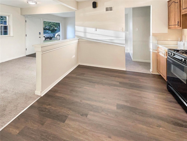 kitchen with kitchen peninsula, black stove, and dark colored carpet