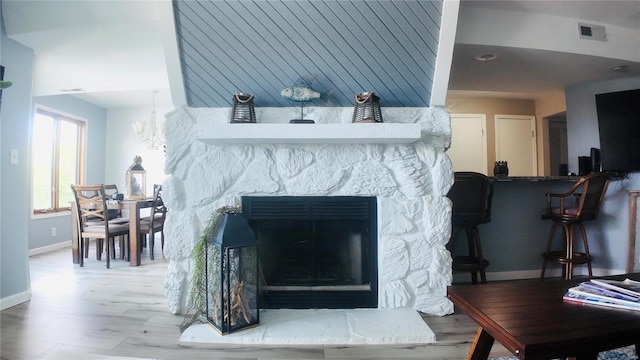 interior details with a chandelier, hardwood / wood-style flooring, and a stone fireplace