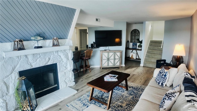 living room featuring a stone fireplace and hardwood / wood-style floors