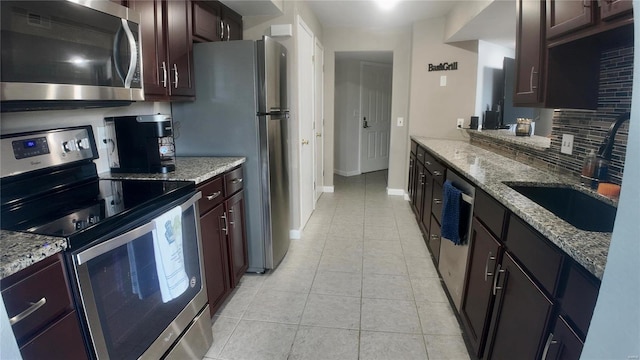 kitchen with light stone countertops, decorative backsplash, sink, appliances with stainless steel finishes, and light tile patterned floors