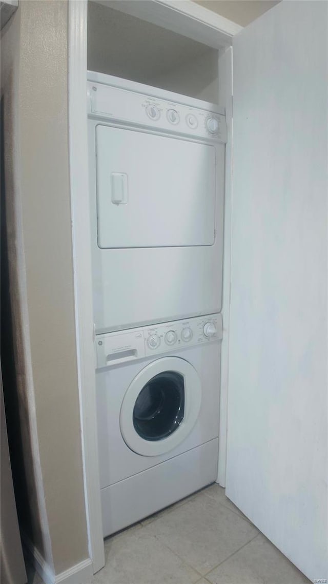 clothes washing area featuring light tile patterned floors and stacked washer / drying machine