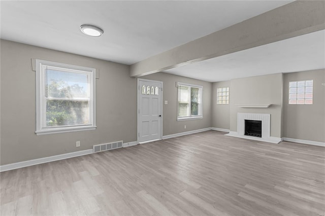 unfurnished living room with a brick fireplace and light hardwood / wood-style floors