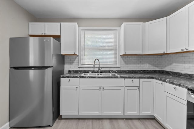 kitchen with stainless steel fridge, backsplash, white cabinetry, and sink