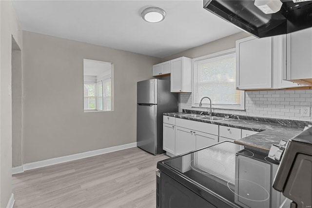 kitchen featuring white cabinets, sink, backsplash, appliances with stainless steel finishes, and light wood-type flooring