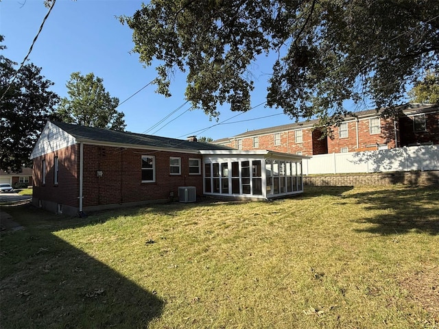 back of property with a yard, a sunroom, and central air condition unit