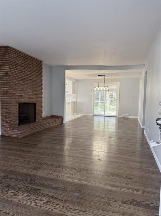 unfurnished living room featuring a brick fireplace and dark hardwood / wood-style flooring