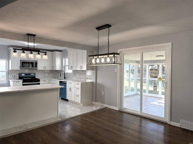 kitchen featuring pendant lighting, tasteful backsplash, white cabinetry, appliances with stainless steel finishes, and light hardwood / wood-style floors