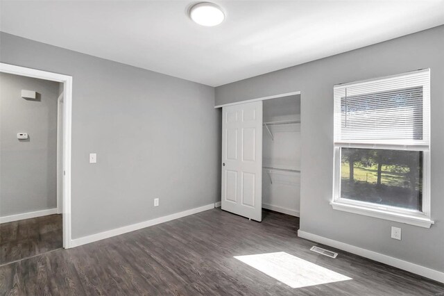 unfurnished bedroom with a closet and dark hardwood / wood-style flooring