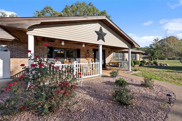 view of front of house with brick siding, a front lawn, and covered porch