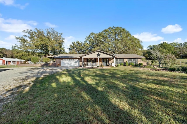 view of front of home with a front lawn, covered porch, a garage, and gravel driveway