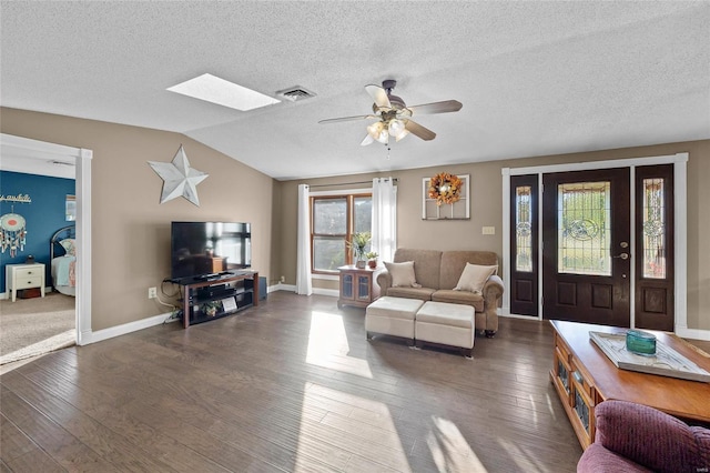 living area featuring vaulted ceiling with skylight, visible vents, wood finished floors, and ceiling fan
