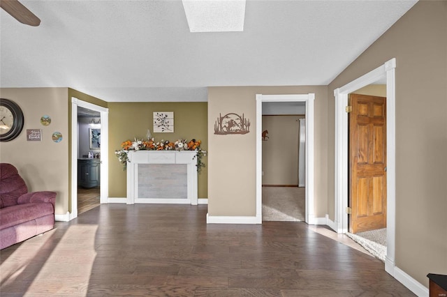 living room with a textured ceiling, wood finished floors, and baseboards