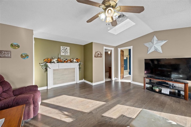 living area with vaulted ceiling with skylight, visible vents, wood finished floors, and ceiling fan