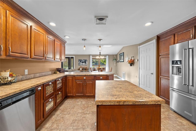 kitchen with a peninsula, a kitchen island, appliances with stainless steel finishes, light countertops, and brown cabinets