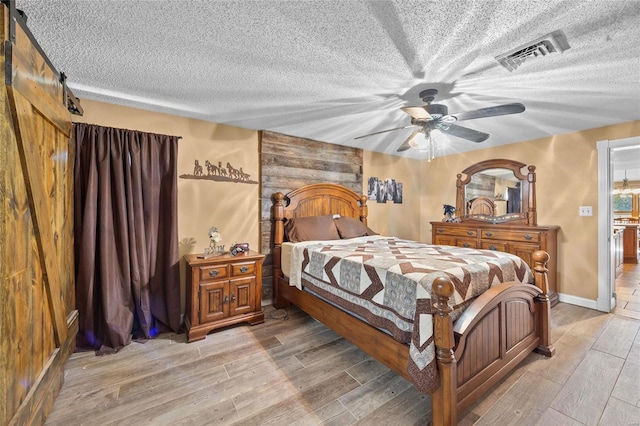 bedroom with visible vents, light wood-style floors, and a textured ceiling
