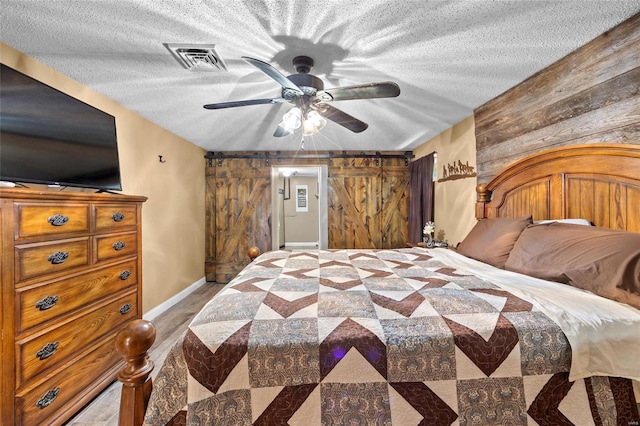 bedroom with a textured ceiling, wood finished floors, wood walls, and visible vents