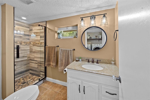 bathroom with washer / clothes dryer, toilet, a textured ceiling, tile patterned flooring, and a stall shower