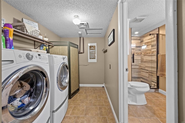 laundry area with washer and dryer, a textured ceiling, light tile patterned flooring, and baseboards