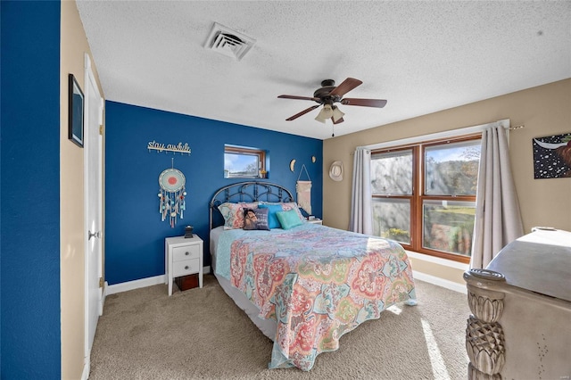bedroom with carpet, visible vents, a textured ceiling, and a ceiling fan