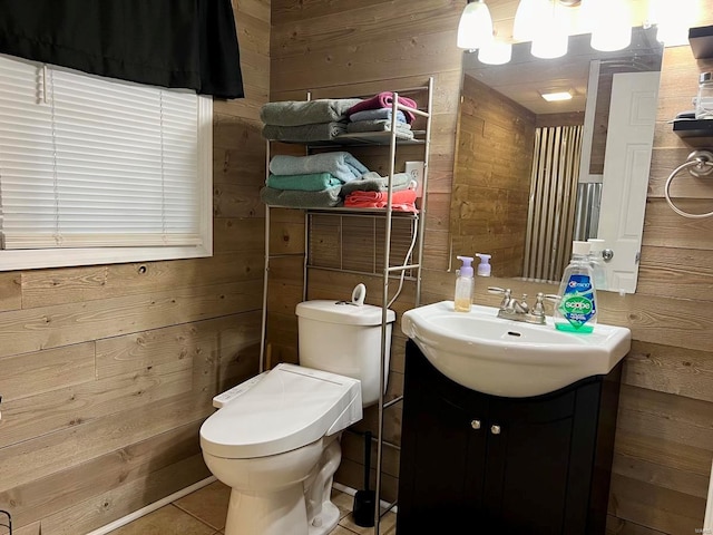 bathroom with vanity, wood walls, and toilet