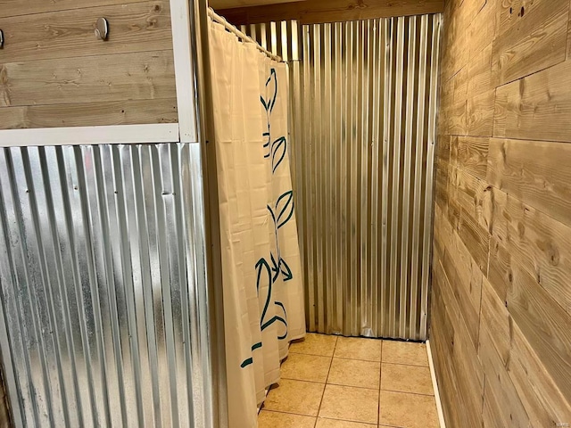 bathroom with tile patterned flooring and wood walls