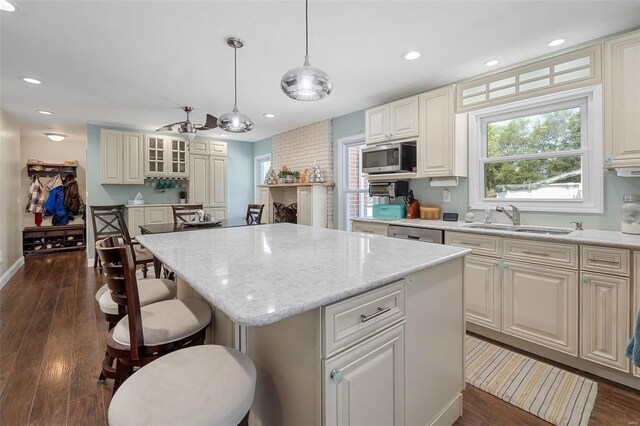 kitchen with a kitchen island, dark hardwood / wood-style flooring, decorative light fixtures, sink, and appliances with stainless steel finishes