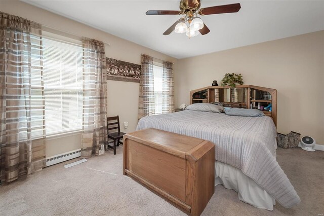 bedroom featuring baseboard heating, multiple windows, ceiling fan, and light colored carpet