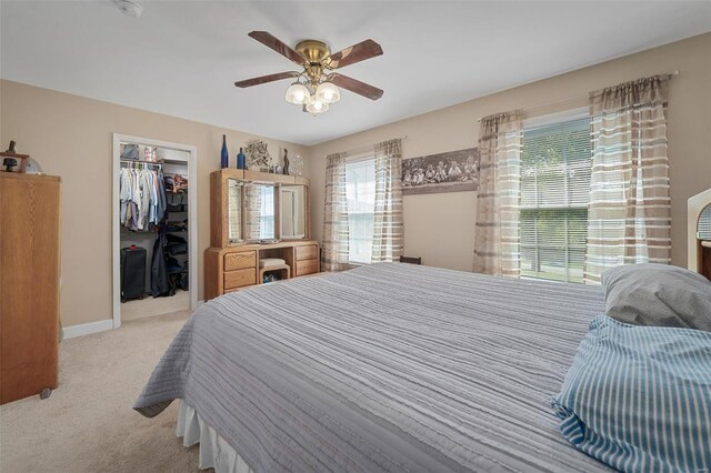 bedroom with multiple windows, ceiling fan, a closet, and light colored carpet