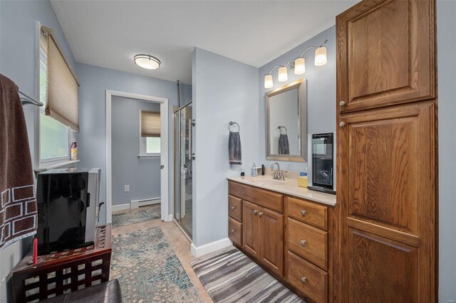 bathroom with a baseboard heating unit, a shower with shower door, and vanity