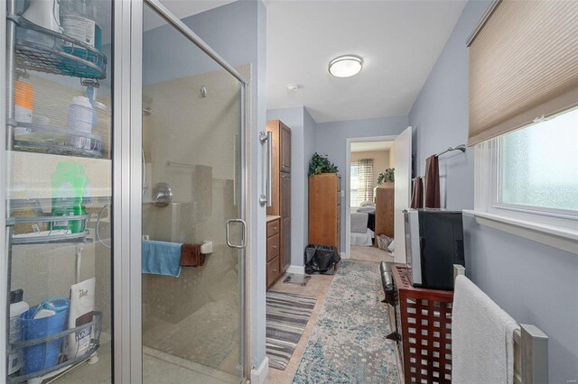 bathroom with a shower with door and a healthy amount of sunlight