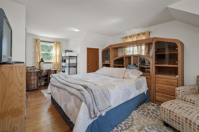 bedroom featuring wood-type flooring and vaulted ceiling