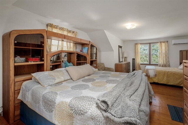 bedroom with dark wood-type flooring and an AC wall unit