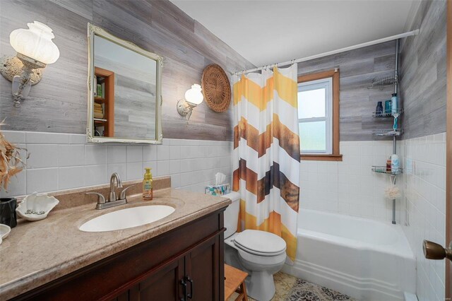 full bathroom with toilet, vanity, shower / tub combo, and tile walls