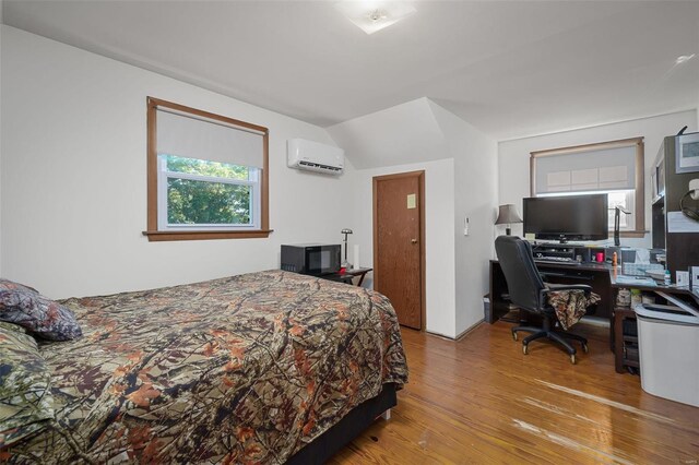 bedroom featuring light wood-type flooring, vaulted ceiling, and a wall unit AC