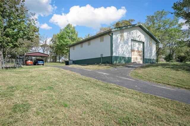 view of side of home with an outdoor structure, a carport, a yard, and a garage