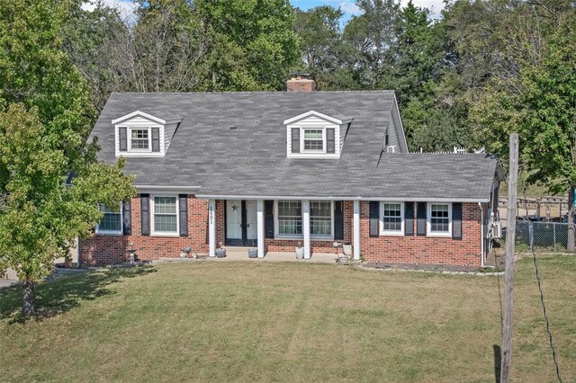 cape cod-style house featuring brick siding, a front lawn, a chimney, and fence