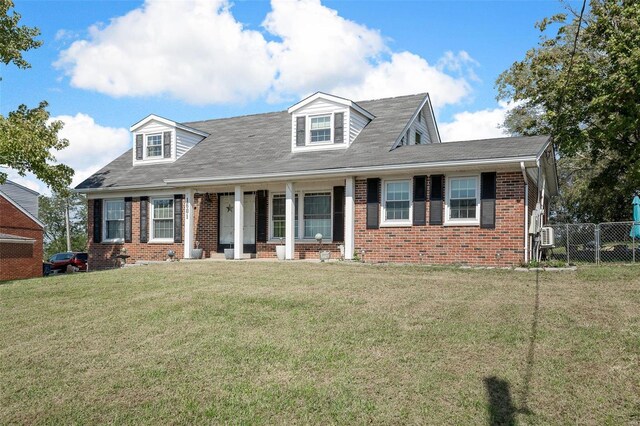 cape cod house with covered porch, brick siding, a front yard, and fence