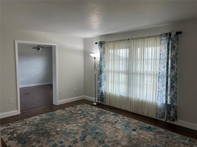 spare room featuring baseboards and wood finished floors