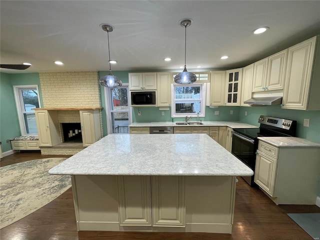 kitchen featuring under cabinet range hood, stainless steel appliances, a kitchen island, a sink, and dark wood-style floors