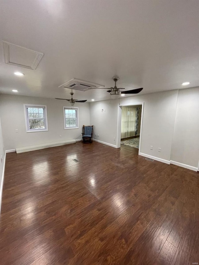 empty room featuring baseboards, wood finished floors, attic access, and a ceiling fan