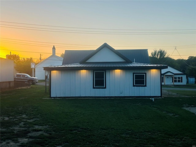 back of property at dusk with a yard, metal roof, and board and batten siding