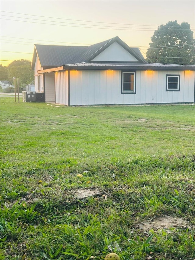 property exterior at dusk with a yard and metal roof