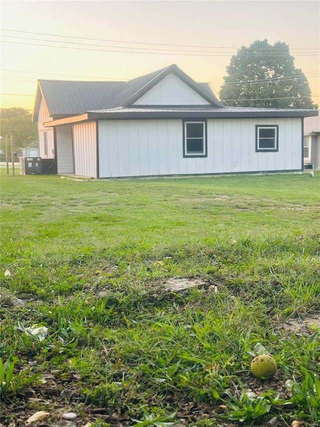 view of property exterior with metal roof and a lawn