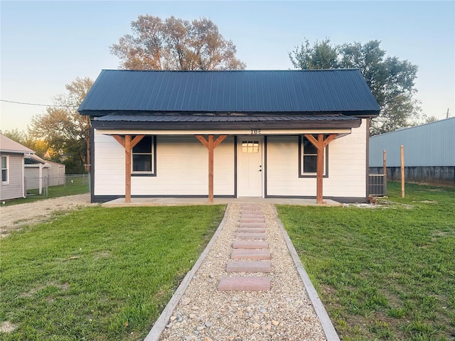 view of front facade with a front lawn, fence, and metal roof