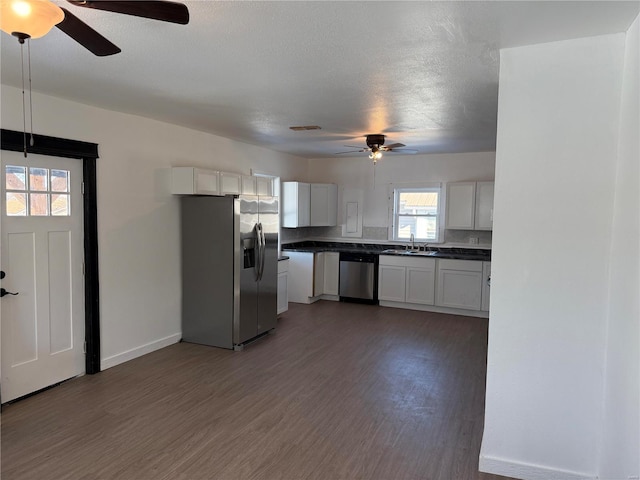 kitchen with a ceiling fan, wood finished floors, dark countertops, a sink, and stainless steel appliances