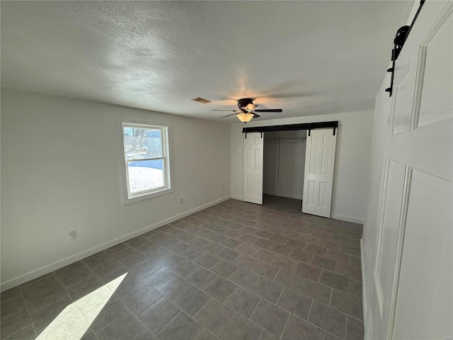 unfurnished bedroom with baseboards, a barn door, and a textured ceiling