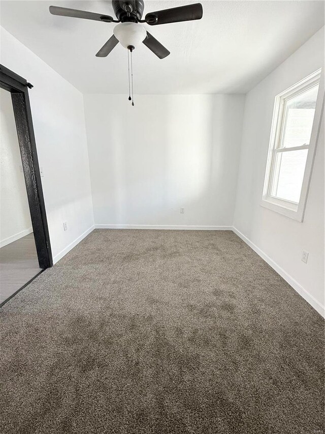 carpeted spare room with baseboards and a ceiling fan