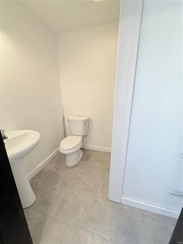 bathroom with toilet, tile patterned flooring, and baseboards